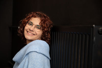 Portrait of young woman standing against wall