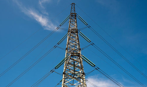 Low angle view of electricity pylon against blue sky