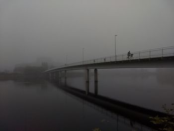 Bridge over river against sky during foggy weather