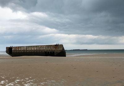 Abandoned built structure on beach against sky