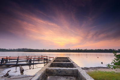 Pier over lake against sky during sunset