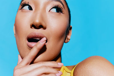 Close-up of young woman with face paint against blue background