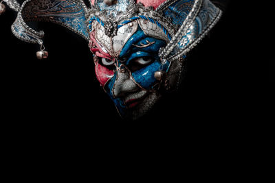 Portrait of woman wearing mask against black background