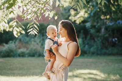 Mother and daughter standing against trees