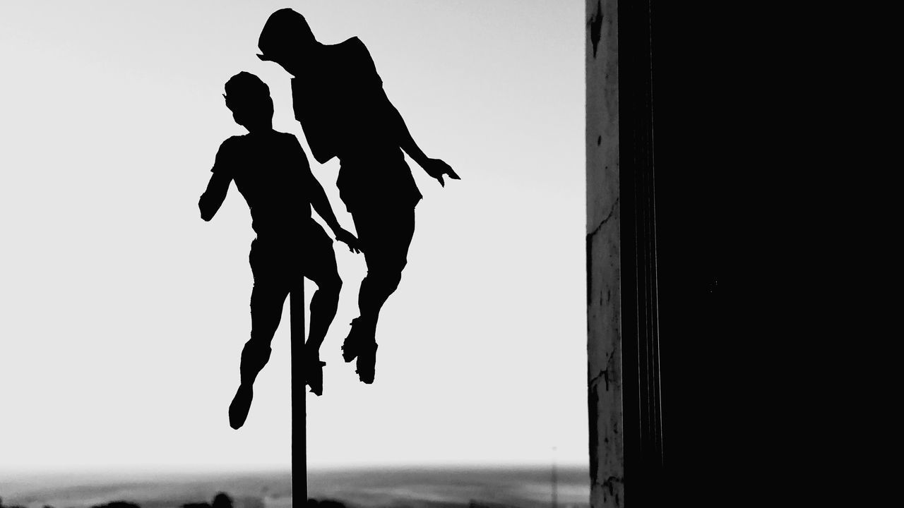 LOW ANGLE VIEW OF SILHOUETTE WOMAN WALKING AGAINST SKY