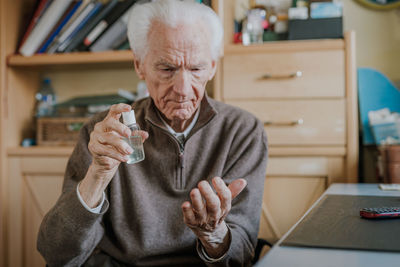Senior man using hand sanitizer at home