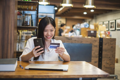 Portrait of young man using mobile phone in restaurant