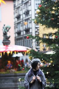 Young woman standing by christmas decoration in city