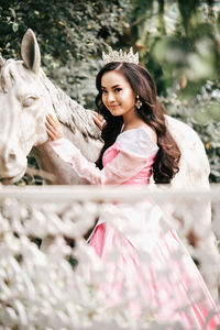 Portrait of beautiful young woman wearing crown standing by sculpture