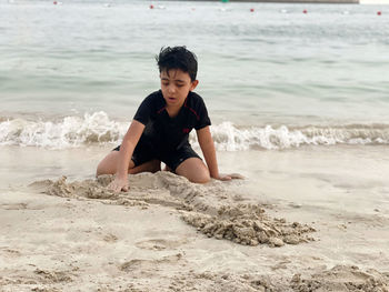 Full length of boy playing on sand at beach