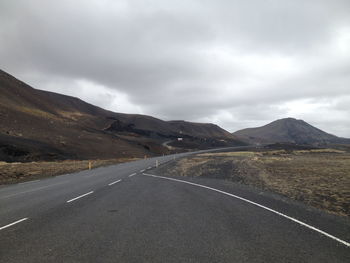 Road by mountains against sky