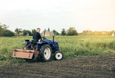 A farmer is driving a tractor across the field. mill grinding machine for soil. land cultivation. 