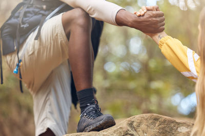 Hands of support and help for hiking couple walking, travel or trekking on rock