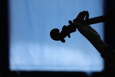 Close-up of silhouette hand playing violin