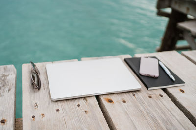 Laptop, mobile phone and notebook by the beach