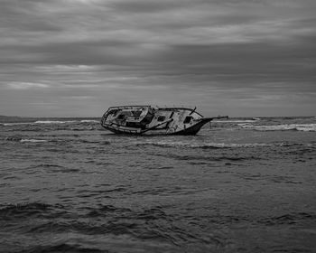 Abandoned boat in sea against sky