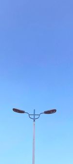 Low angle view of telephone pole against clear blue sky