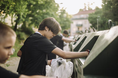 Teenage boy putting garbage in recycling bin