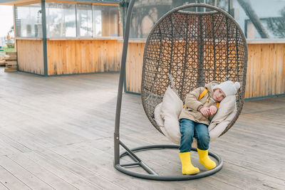 Little girl sat down to rest after a walk in a rattan chair outdoors in a warm autumn, spring. child