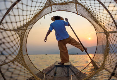 Rear view of man standing on beach during sunset