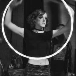 Young woman looking away while standing in mirror