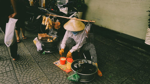 Woman wearing asian style conical hat selling food in market