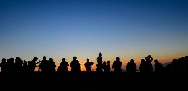 Silhouette people looking at sunset