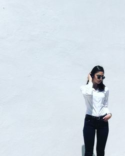 Portrait of young woman standing against wall