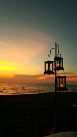 Silhouette lifeguard hut on beach against sky during sunset