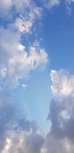 Low angle view of sunlight streaming through clouds