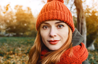 Autumn fashion portrait of stylish woman in bright orange knitted hat and scarf. red hair