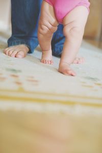 Low section of parent with baby on carpet at home
