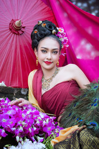 Portrait of beautiful young woman with pink orchids wearing traditional clothing