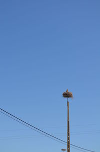 Low angle view of electricity pylon against clear blue sky