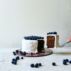 Cake and blueberries on table against wall