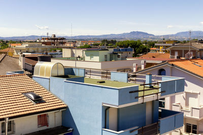 High angle view of buildings in city against blue sky