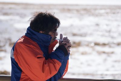 Mature man igniting cigarette against sea