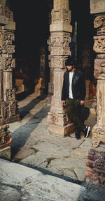 Full length of senior woman amidst buildings at temple