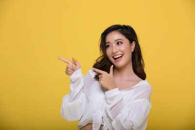 Portrait of a smiling young woman against yellow background