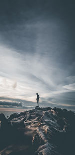 Silhouette man standing on rock against sky