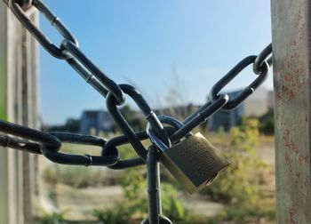 Close-up of padlock hanging on chain against sky