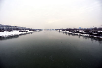 Scenic view of river by city against sky