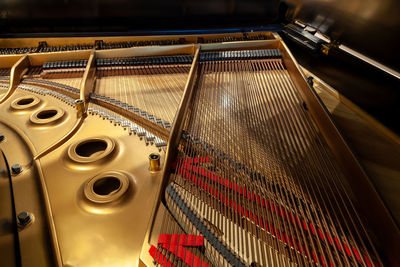 Inside of a small baby grand piano with strings and brass coloring un close.