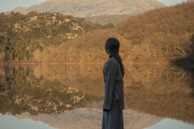 Rear view of man standing against lake