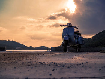 People sitting on land against sky during sunset