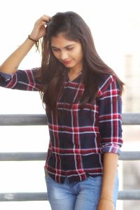 Young woman looking down while standing against wall