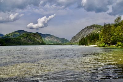 Scenic view of lake and mountains against cloudy sky