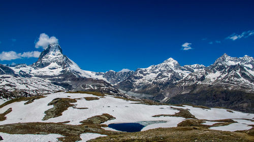 Scenic view of snowcapped mountains against blue sky