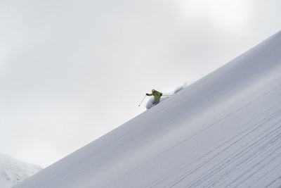 Low angle view of person on snowcapped mountain against sky