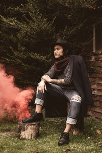 Portrait of a man sitting on a wood log